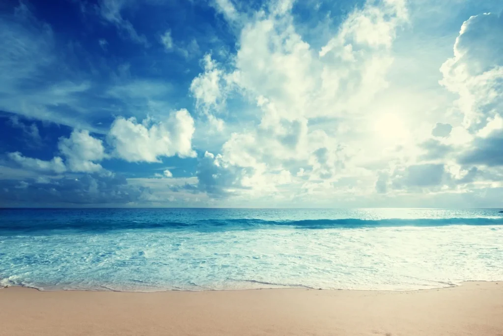 A beach with the ocean and clouds in the sky.